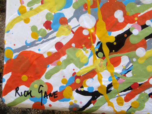 Abstract radial burst painting with dense splatters and streaks of yellow, orange, white, blue, pink, red, and green radiating outward from a bright central area, on 80 by 60 cm canvas - detail
