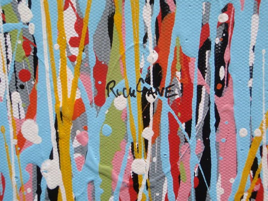 Abstract wall art featuring the word 'JOY' formed by dripping, splattered paint in multiple colours including red, blue, yellow, black, and white on a light background - detail