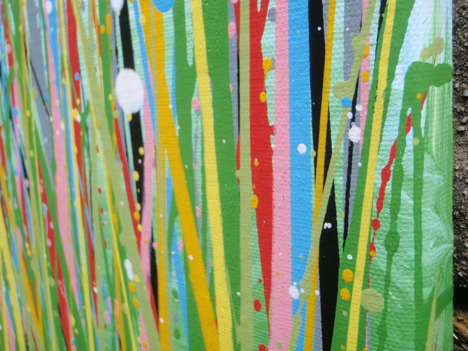 A colourful abstract painting of a grassy field with tall green, yellow, and red strokes, dotted with red, blue, orange, and pink flowers, beneath a light blue sky with white paint splatter. Hand-painted on to a large 100 by 70 cm canvas - detail