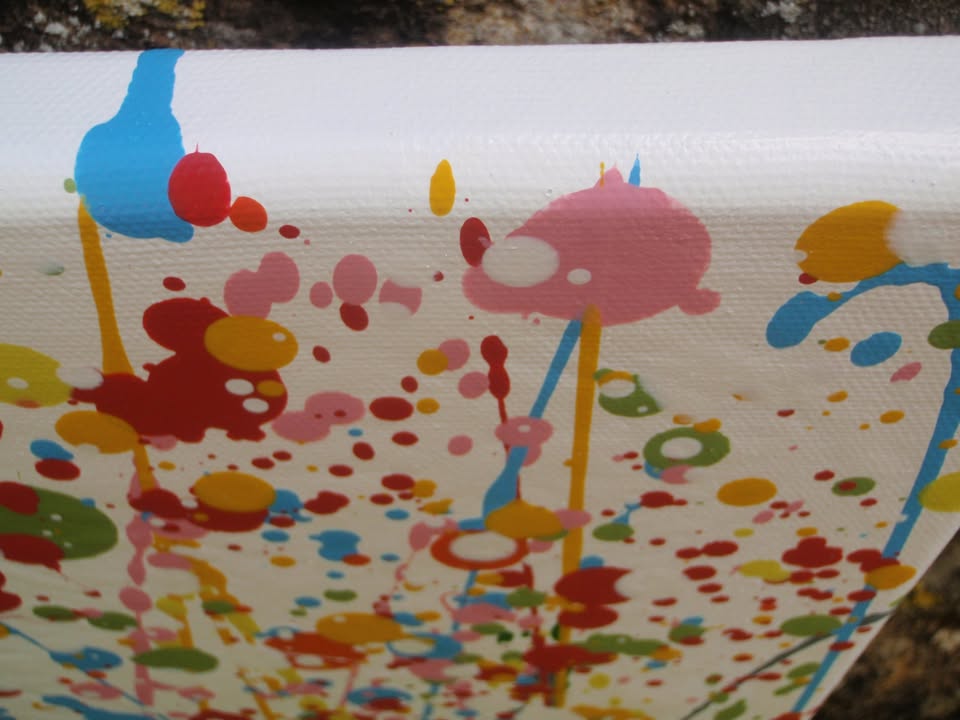 Abstract floral field painting with green grass-like strokes and many red, yellow, blue, and pink flower-like splatters on a white background - detail