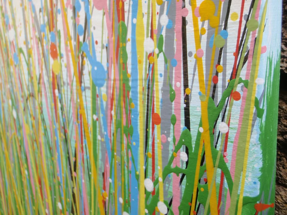 A colourful abstract painting of a grassy field under a blue sky, with splashes of pink, yellow, blue, green, and orange dots and lines throughout, hand-painted on to a large canvas - detail