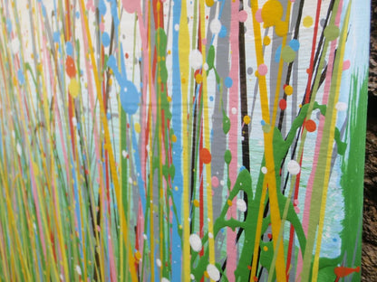 A colourful abstract painting of a grassy field under a blue sky, with splashes of pink, yellow, blue, green, and orange dots and lines throughout, hand-painted on to a large canvas - detail