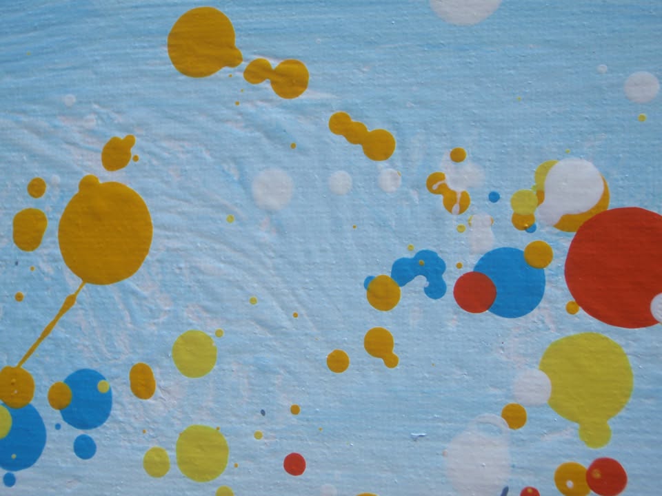 A colourful abstract landscape painting depicting a field of tall grass under a blue sky, with splatters and drips of yellow, red, orange, blue, pink, and green paint throughout. Hand-painted on to a large 101.5 by 81 cm stretched canvas - detail