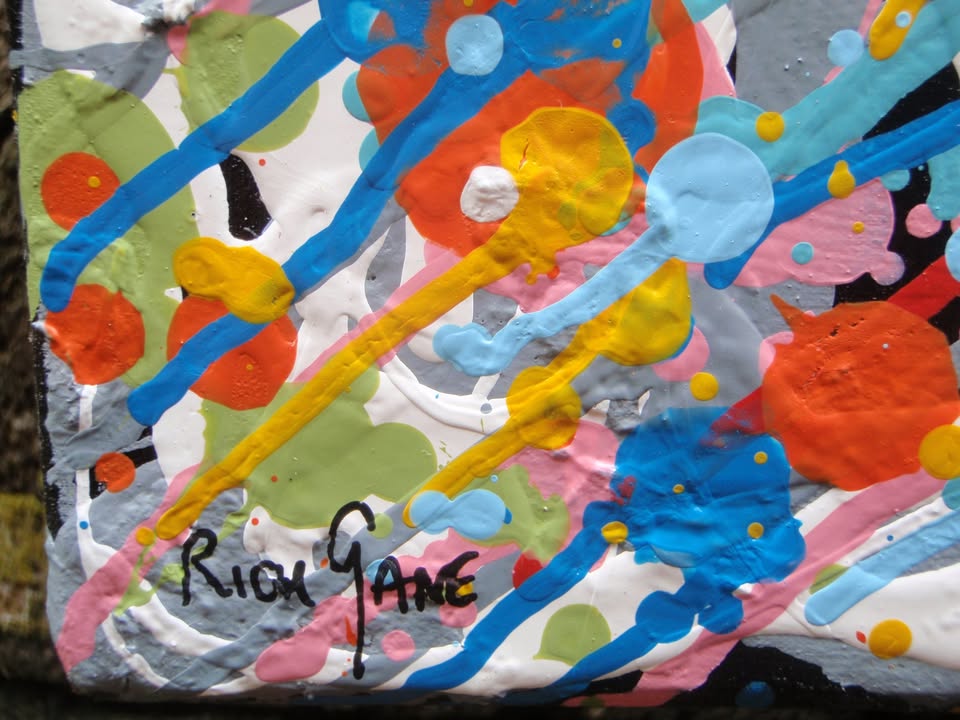 Unique abstract radial artwork filled with dense splatters and streaks of blue, red, orange, yellow, black, and white radiating from a bright white centre, on a 150 by 100 cm framed canvas - detail