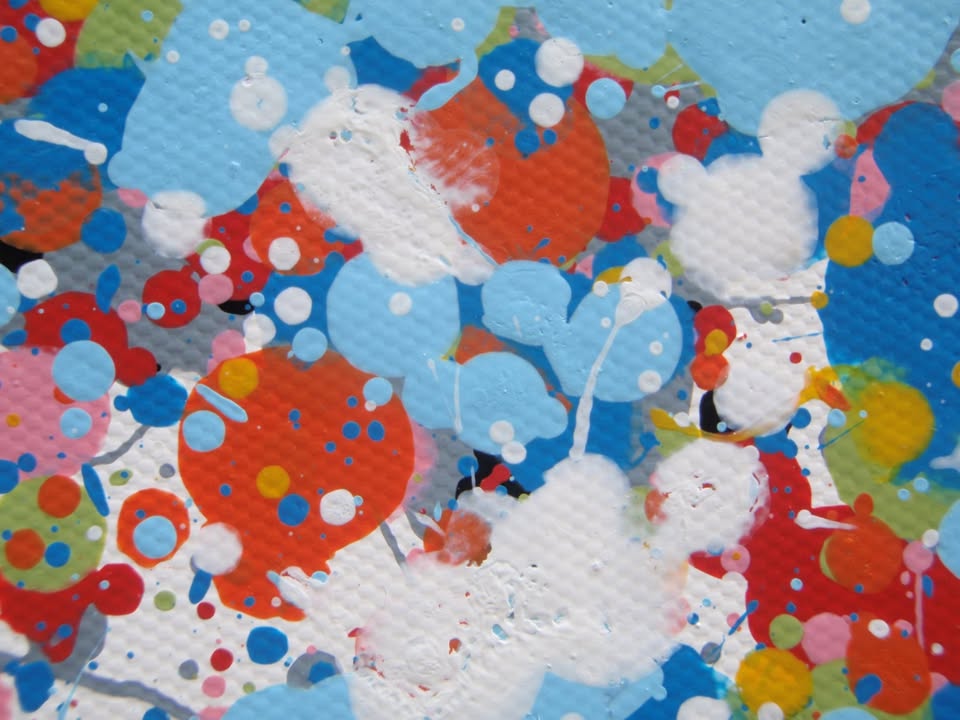 A rectangular abstract art painting featuring a dense seascape of multicoloured speckles, with a prominent horizontal band of white and light blue in the centre and denser blue speckling around the edges. Hand-painted on to a 250 by 112 cm un-stretched canvas. Detail.