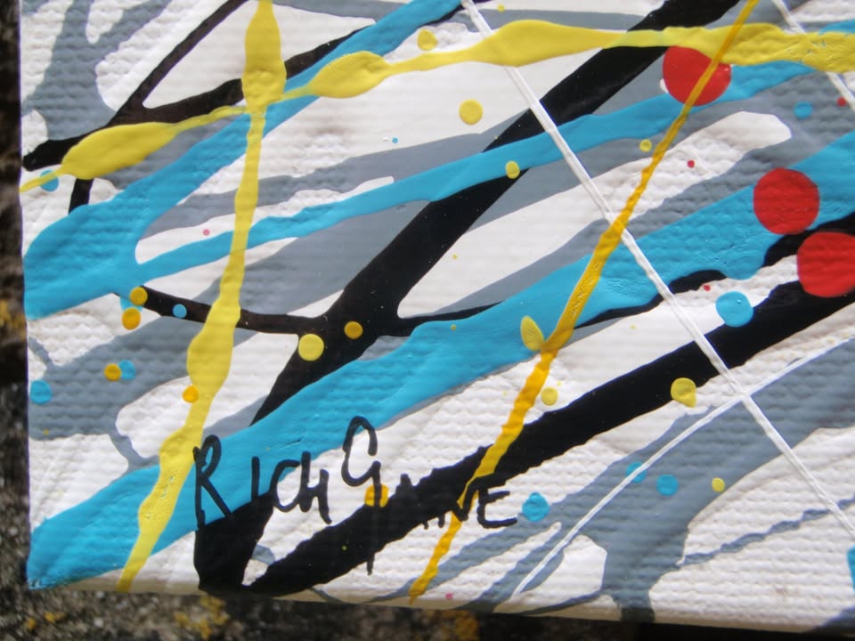 Abstract expressionist painting featuring a dense, circular composition of energetic splatters, drips, and intersecting lines in yellow, white, red, blue, black, and orange. Hand-painted by me, Rich Gane, on to a large, framed, 80 by 60 cm canvas - detail