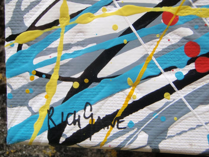 Abstract expressionist painting featuring a dense, circular composition of energetic splatters, drips, and intersecting lines in yellow, white, red, blue, black, and orange. Hand-painted by me, Rich Gane, on to a large, framed, 80 by 60 cm canvas - detail