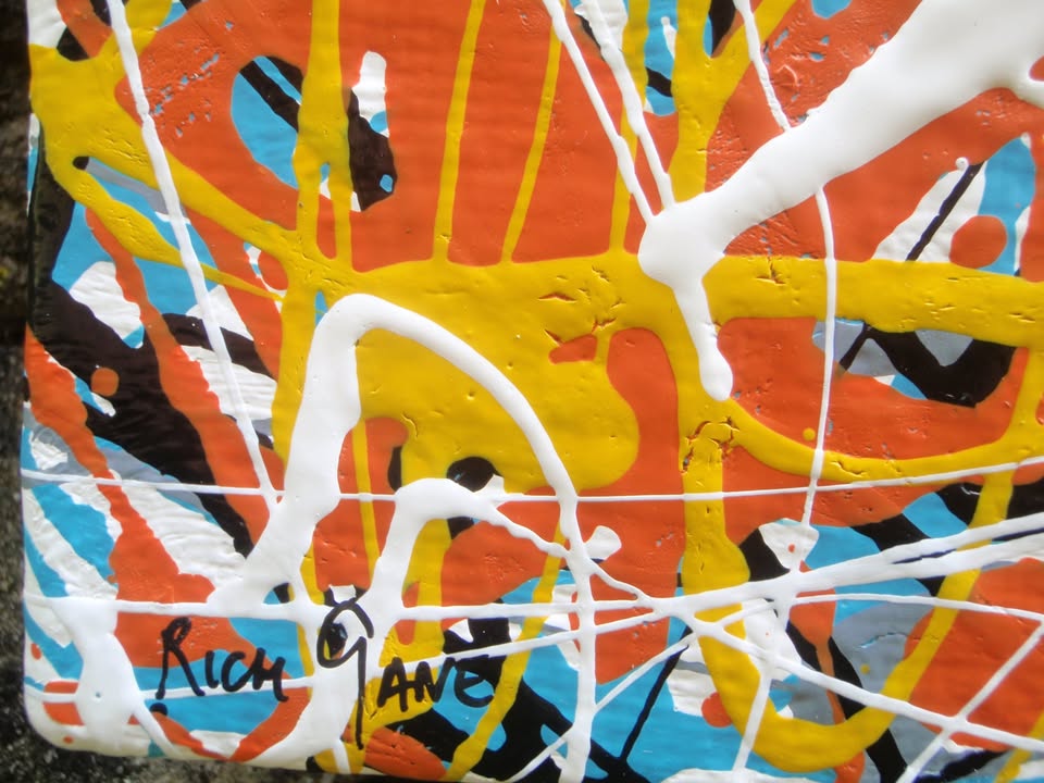 An abstract painting filled with dense, energetic splatters and drips in orange, yellow, white, black, and light blue, hand-painted on to a large framed wooden panel - detail