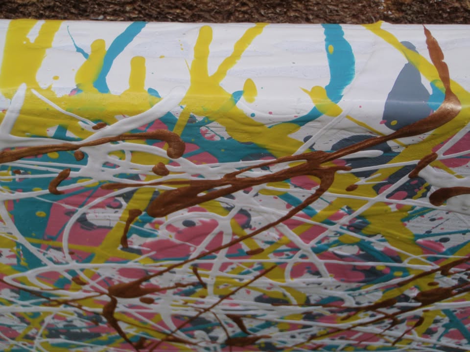 Abstract multi-colour paint splatter and drip artwork with dense white, pink, yellow, blue, and metallic gold across the full 143 by 100 cm framed canvas - detail