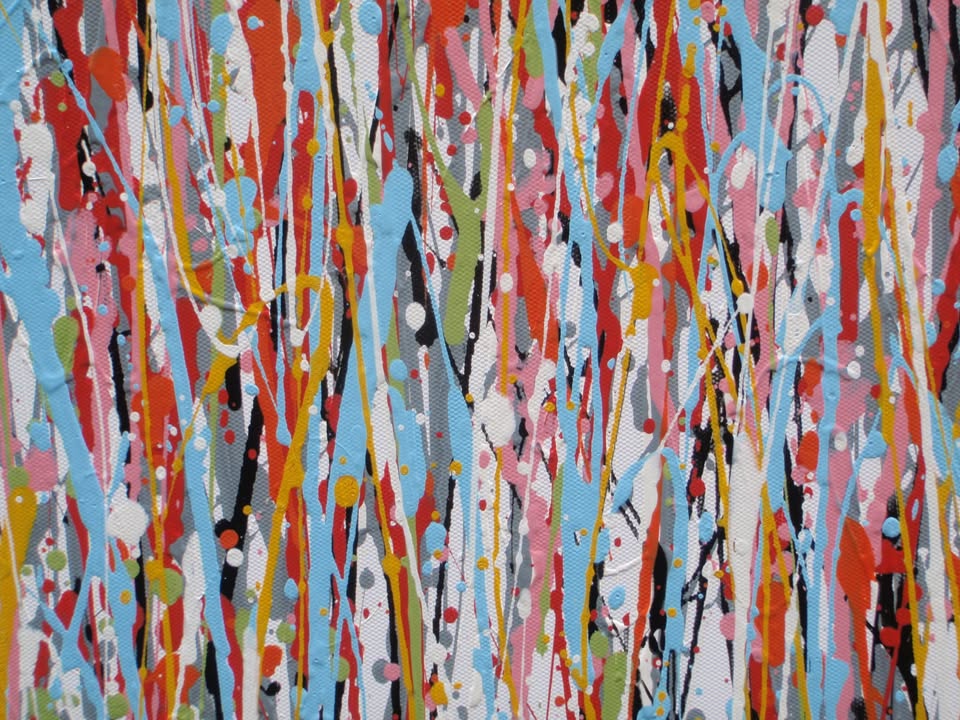 Abstract wall art featuring the word 'JOY' formed by dripping, splattered paint in multiple colours including red, blue, yellow, black, and white on a light background - detail